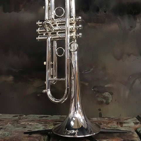 Silver trumpet on a stand with a dark, textured background